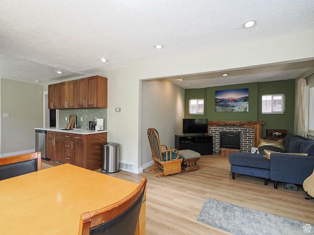 320 E Hollywood Ave S, Salt Lake City, UT 84115 - kitchen with a textured ceiling, light wood-style flooring, light countertops, dishwasher, and a brick fireplace