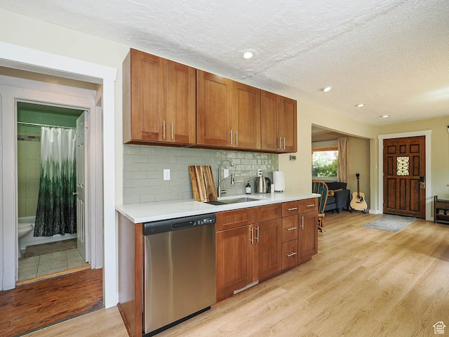 320 E Hollywood Ave S, Salt Lake City, UT 84115 - kitchen with stainless steel dishwasher, light countertops, light wood-type flooring, brown cabinetry, and a textured ceiling