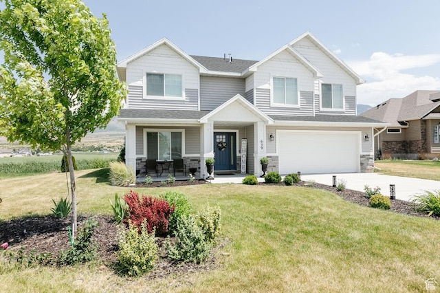 659 S Lakeside Dr, Franklin, ID 83237 - view of front facade featuring stone siding, a garage, driveway, covered porch, and a front lawn