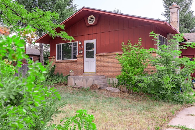 570 N 400 W, Logan, UT 84321 - view of front of house featuring a chimney, brick siding, board and batten siding, and entry steps
