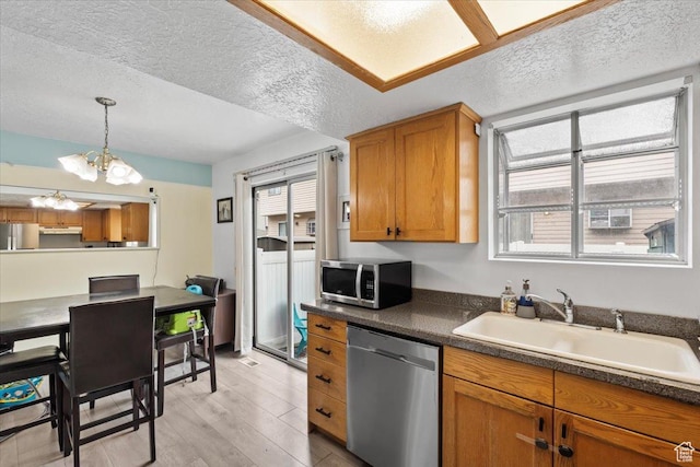 1124 S 1000 E Unit 3, Provo, UT 84606 - kitchen featuring stainless steel appliances, under cabinet range hood, a textured ceiling, a chandelier, and brown cabinetry