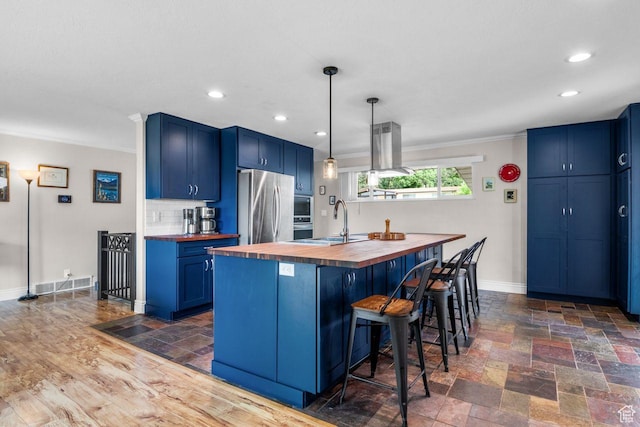 784 Lavina Dr, South Ogden, UT 84403 - kitchen featuring butcher block countertops, freestanding refrigerator, blue cabinets, an island with sink, and recessed lighting