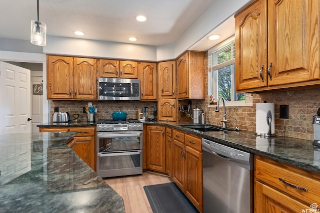 2484 W Gordon Ave, Layton, UT 84041 - kitchen featuring stainless steel appliances, brown cabinets, dark stone countertops, light wood-type flooring, and decorative backsplash
