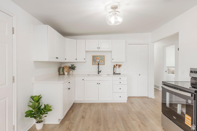 5655 S 700 W, Murray, UT 84123 - kitchen featuring stainless steel electric range, light countertops, light wood-type flooring, and white cabinetry