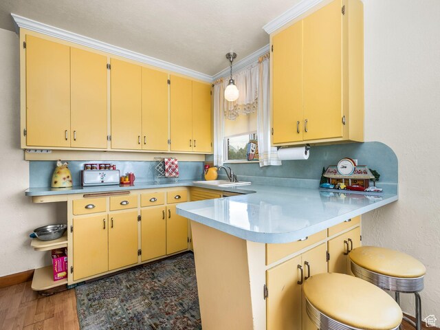 920 S 150 E, Orem, UT 84058 - kitchen featuring a peninsula, light countertops, dark wood finished floors, decorative light fixtures, and a kitchen bar