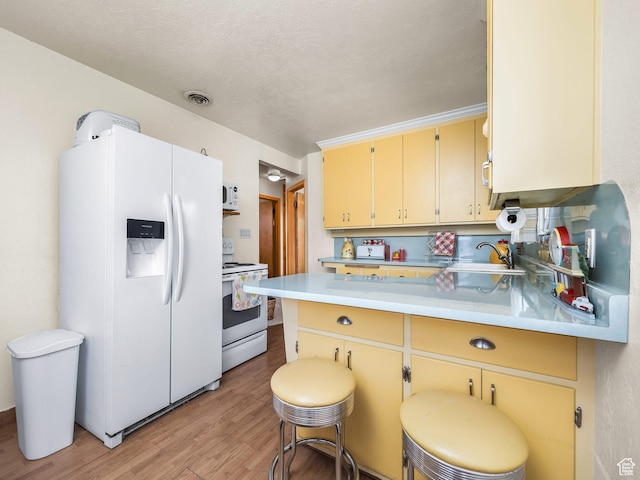 920 S 150 E, Orem, UT 84058 - kitchen with white appliances, a peninsula, light wood finished floors, light countertops, and a kitchen breakfast bar