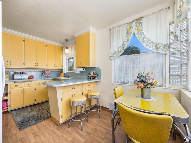 920 S 150 E, Orem, UT 84058 - kitchen with light wood finished floors, a peninsula, light countertops, pendant lighting, and ornamental molding