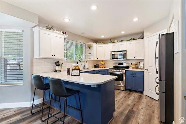 707 W 3675 S, Riverdale, UT 84405 - kitchen with stainless steel appliances, a peninsula, decorative backsplash, white cabinets, and a kitchen bar