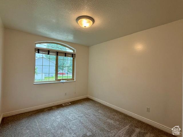 943 W Majestic, Logan, UT 84321 - spare room with a textured ceiling and dark carpet