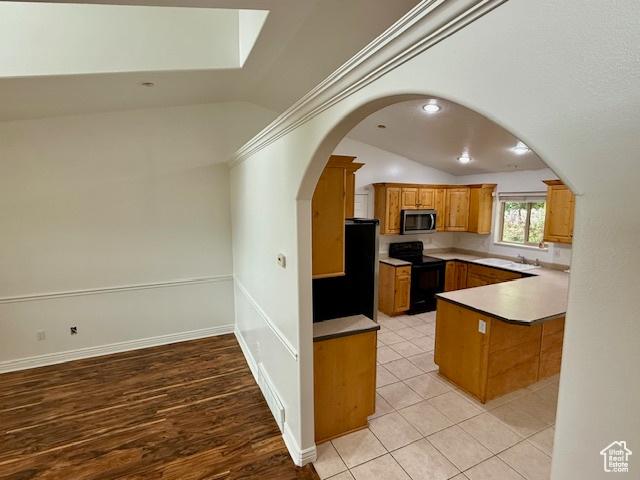 943 W Majestic, Logan, UT 84321 - kitchen featuring stainless steel microwave, lofted ceiling, black range with electric stovetop, brown cabinetry, and arched walkways