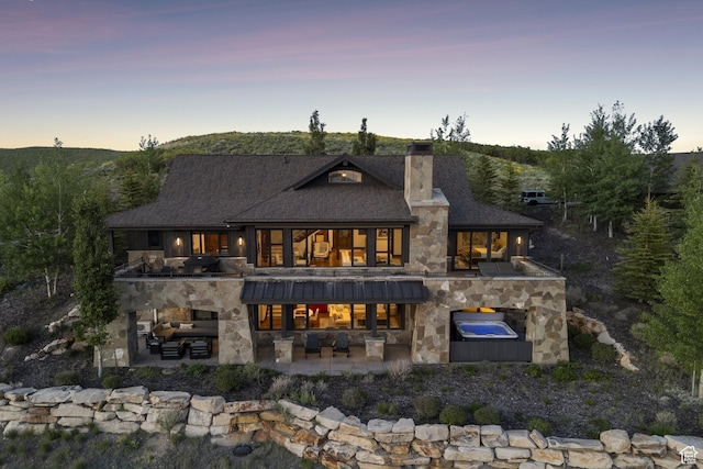 9079 Dye Cabins Dr, Park City, UT 84098 - back of property at dusk featuring a balcony, stone siding, a patio, and outdoor lounge area
