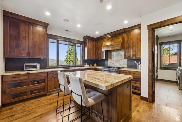 9079 Dye Cabins Dr, Park City, UT 84098 - kitchen with custom exhaust hood, backsplash, a kitchen island, wood finished floors, and a breakfast bar area