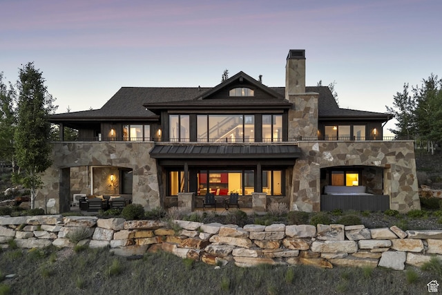 9079 Dye Cabins Dr, Park City, UT 84098 - back of house at dusk with stone siding, a balcony, a patio area, a chimney, and an outdoor living space with a fireplace