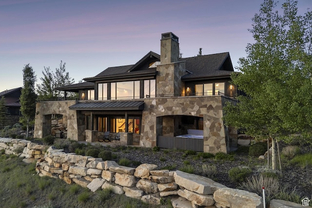 9079 Dye Cabins Dr, Park City, UT 84098 - back of property at dusk featuring stone siding, an outdoor stone fireplace, a patio area, a chimney, and a balcony
