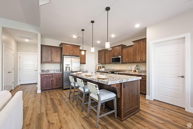 886 N Sandy Talus Dr, Washington, UT 84780 - kitchen with stainless steel appliances, light wood-style flooring, a kitchen bar, a center island with sink, and pendant lighting