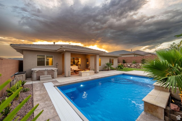886 N Sandy Talus Dr, Washington, UT 84780 - pool at dusk featuring a covered hot tub, a patio area, and a fenced backyard