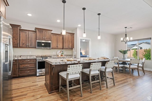 886 N Sandy Talus Dr, Washington, UT 84780 - kitchen with appliances with stainless steel finishes, light wood finished floors, a center island with sink, a kitchen bar, and recessed lighting
