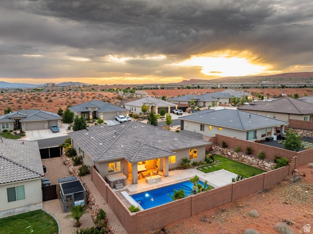 886 N Sandy Talus Dr, Washington, UT 84780 - pool at dusk featuring a fenced backyard, a residential view, a mountain view, a patio, and area for grilling