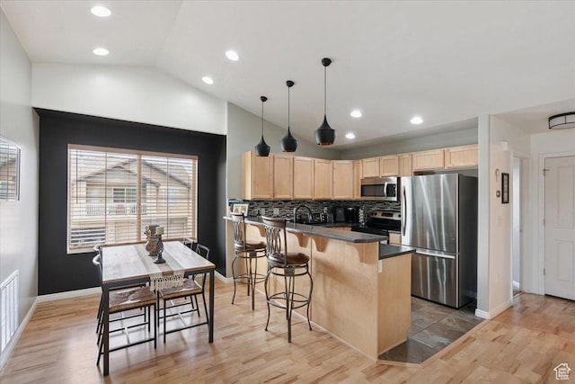 1049 W Allington Dr N, North Salt Lake, UT 84054 - kitchen featuring appliances with stainless steel finishes, light brown cabinetry, a peninsula, dark countertops, and lofted ceiling