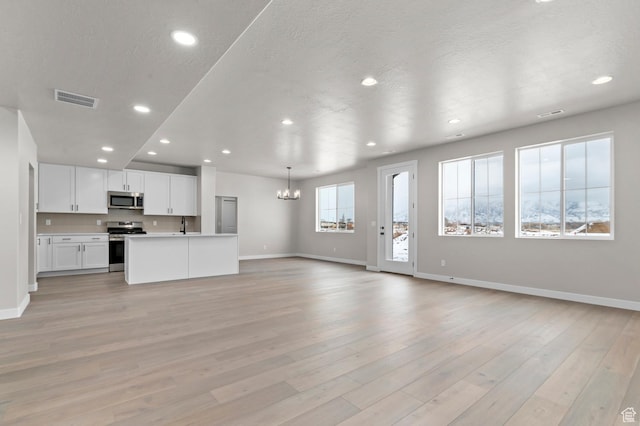 1918 S 2475 W, West Haven, UT 84401 - unfurnished living room with a chandelier, recessed lighting, and light wood-style floors