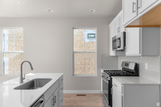 3932 W 2800 N, Lehi, UT 84043 - kitchen featuring stainless steel appliances, light wood-style floors, tasteful backsplash, light countertops, and plenty of natural light