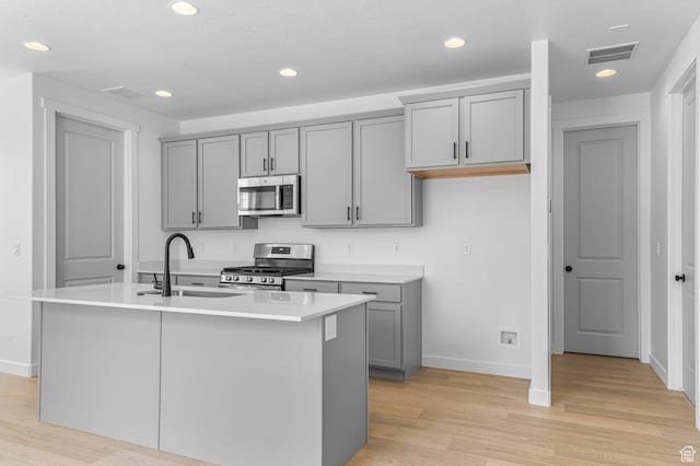 3908 W 2720 N, Lehi, UT 84043 - kitchen with appliances with stainless steel finishes, gray cabinetry, light wood finished floors, an island with sink, and recessed lighting