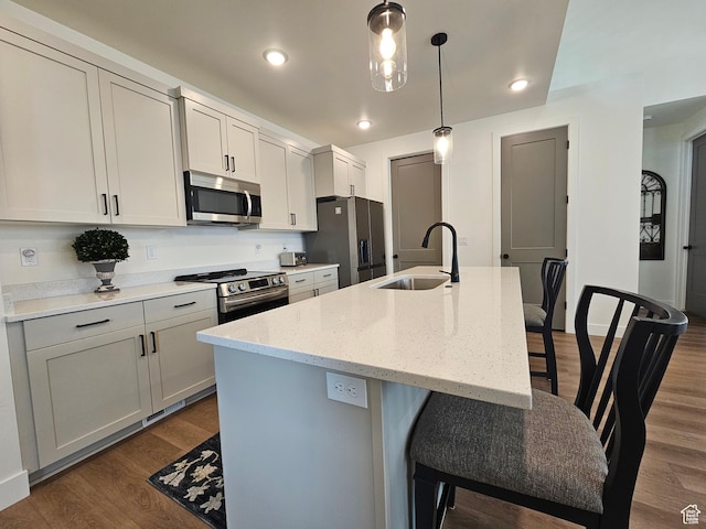 964 E 50 S, Santaquin, UT 84655 - kitchen with appliances with stainless steel finishes, dark wood finished floors, a center island with sink, a kitchen bar, and decorative light fixtures