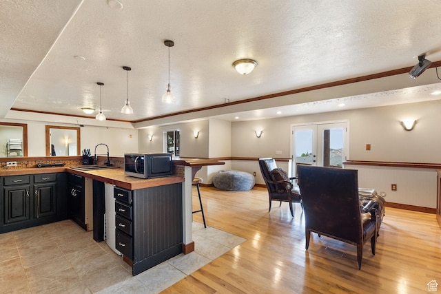 2151 E Village Vista Dr, Draper, UT 84020 - kitchen featuring black microwave, butcher block countertops, a textured ceiling, light wood-style floors, and a kitchen bar