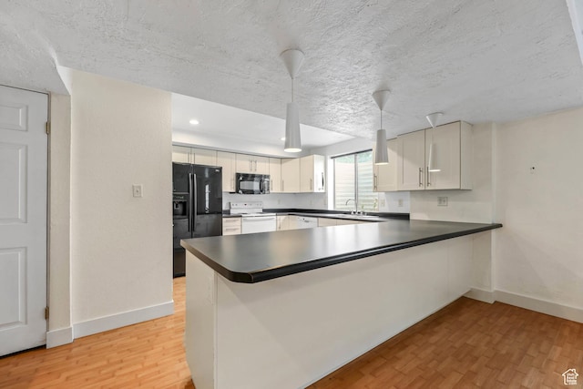 9448 S Lady Dove Ln, South Jordan, UT 84095 - kitchen with black appliances, light wood-style floors, a peninsula, dark countertops, and a textured ceiling
