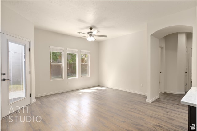 2866 E Carmine Dr, St George, UT 84790 - unfurnished living room with arched walkways, a ceiling fan, plenty of natural light, and wood finished floors