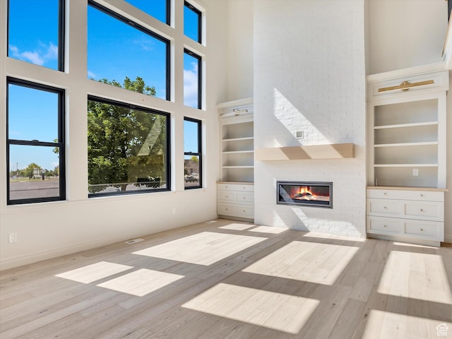 1395 N 330 E Unit 3, Orem, UT 84057 - unfurnished living room with a towering ceiling, built in shelves, a brick fireplace, and wood finished floors