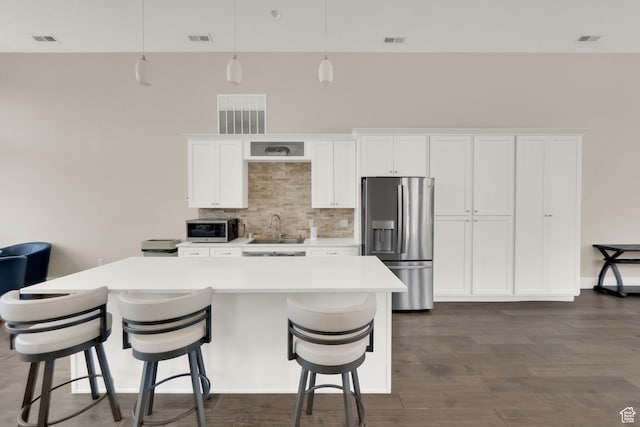 10376 S Beetdigger Blvd, Sandy, UT 84070 - kitchen with stainless steel appliances, a kitchen island, white cabinets, light countertops, and tasteful backsplash