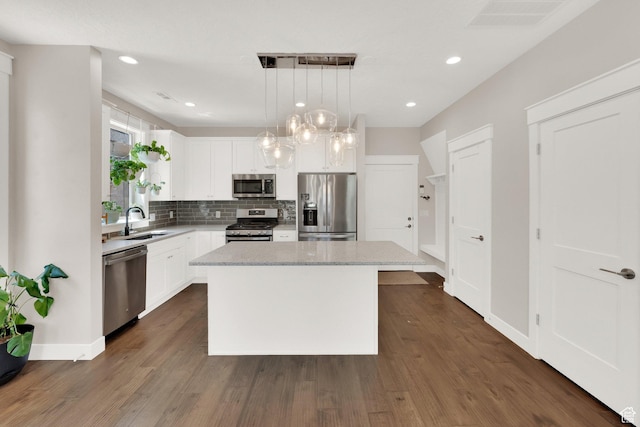 10376 S Beetdigger Blvd, Sandy, UT 84070 - kitchen featuring appliances with stainless steel finishes, a kitchen island, tasteful backsplash, white cabinets, and dark wood-style flooring