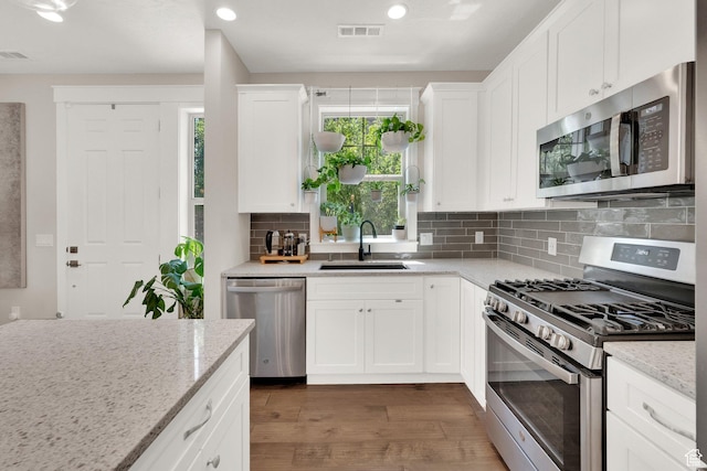 10376 S Beetdigger Blvd, Sandy, UT 84070 - kitchen with appliances with stainless steel finishes, wood finished floors, white cabinets, tasteful backsplash, and recessed lighting