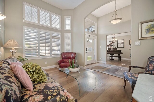 10025 Silver Streak Dr, South Jordan, UT 84095 - living room with arched walkways, a chandelier, a high ceiling, wood finished floors, and plenty of natural light