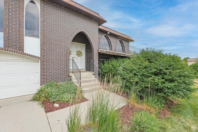 8614 S Buena Vista Dr E, Sandy, UT 84094 - view of exterior entry featuring brick siding, a balcony, and a garage