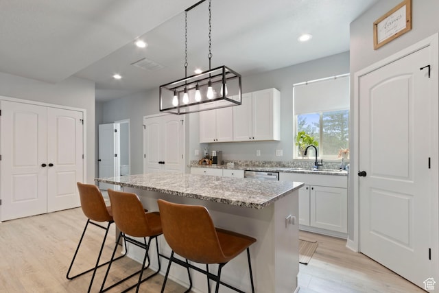 1288 Lincoln Ave, Ogden, UT 84404 - kitchen with light wood-style floors, a center island, recessed lighting, a kitchen breakfast bar, and light stone counters