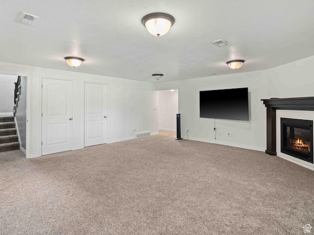 3552 S 5250 W Unit 13, Hooper, UT 84315 - unfurnished living room with carpet, stairs, a textured ceiling, and a glass covered fireplace