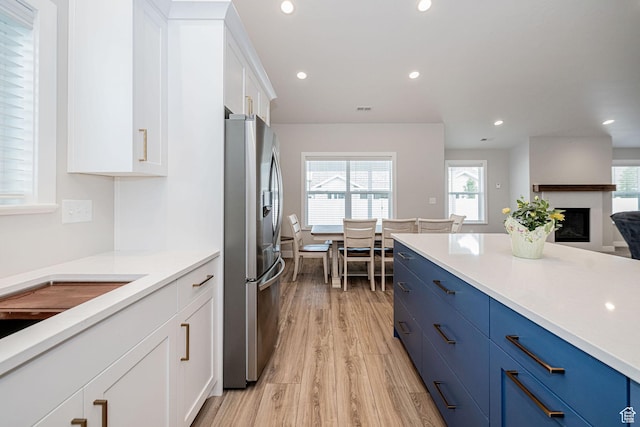 318 E 290 N, Preston, ID 83263 - kitchen featuring stainless steel fridge with ice dispenser, blue cabinetry, light wood-style floors, white cabinetry, and light countertops