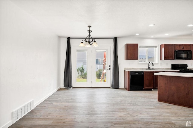 496 S 1600 E, Hyrum, UT 84319 - kitchen featuring black appliances, a chandelier, light countertops, light wood-style flooring, and decorative light fixtures