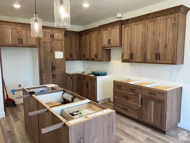 1966 W 4750 N Unit 7, Enoch, UT 84721 - kitchen featuring light wood finished floors, decorative light fixtures, brown cabinets, recessed lighting, and a center island