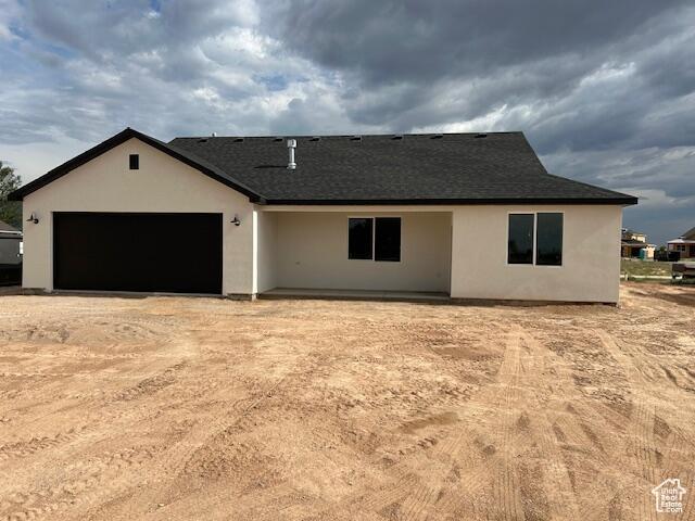 1966 W 4750 N Unit 7, Enoch, UT 84721 - view of front of house with stucco siding, an attached garage, roof with shingles, and dirt driveway