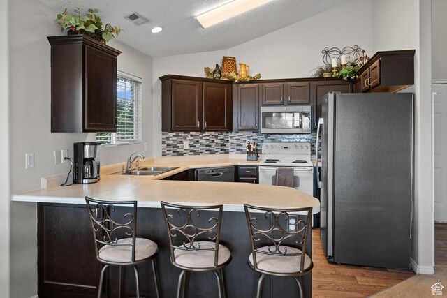 141 W Suncrest Ln, Saratoga Springs, UT 84045 - kitchen featuring stainless steel appliances, a peninsula, dark brown cabinetry, light countertops, and a kitchen bar