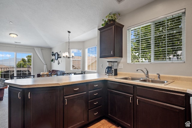 141 W Suncrest Ln, Saratoga Springs, UT 84045 - kitchen with a peninsula, light countertops, dark brown cabinetry, a textured ceiling, and a chandelier