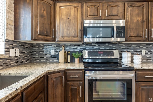 9768 N 5520 W, Highland, UT 84003 - kitchen with stainless steel appliances, backsplash, light stone countertops, and dark brown cabinetry