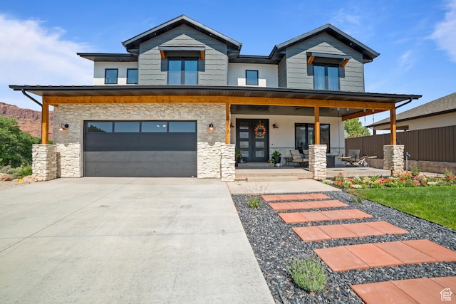3317 S Watchman Trl, Moab, UT 84532 - contemporary home featuring stone siding, a porch, concrete driveway, and an attached garage