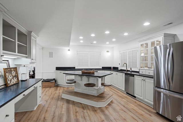 5040 S 1450 E, Ogden, UT 84403 - kitchen featuring appliances with stainless steel finishes, dark countertops, glass insert cabinets, light wood-style floors, and recessed lighting