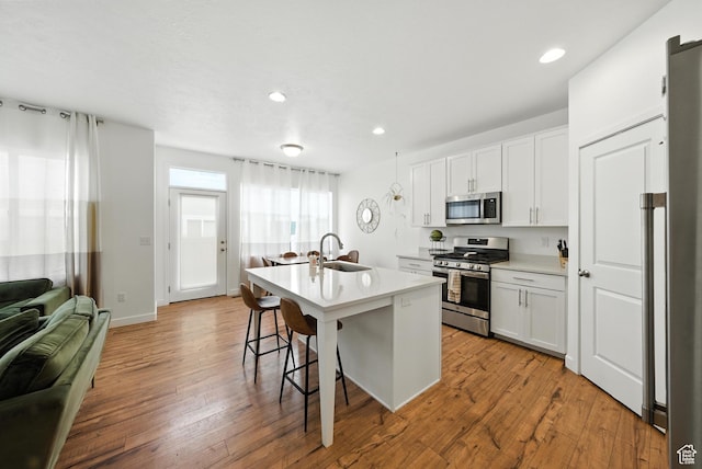 15104 S Halter Way, Bluffdale, UT 84065 - kitchen featuring appliances with stainless steel finishes, a breakfast bar area, a kitchen island with sink, light wood-type flooring, and recessed lighting