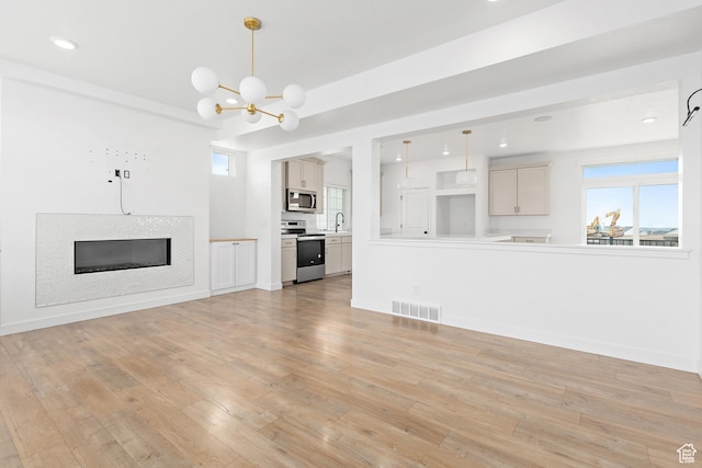 4397 W Bromwell Ct, Lehi, UT 84043 - unfurnished living room featuring light wood-type flooring, a chandelier, recessed lighting, and a glass covered fireplace