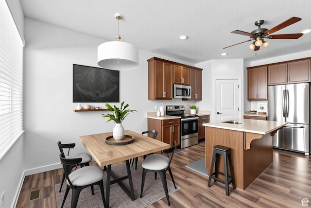 15218 S Tack Way, Bluffdale, UT 84065 - kitchen featuring stainless steel appliances, light countertops, an island with sink, ceiling fan, and a kitchen breakfast bar